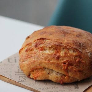 Close-up of a rustic sourdough bread loaf on wax paper, perfect for culinary presentations.