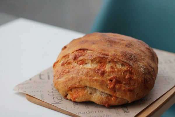 Close-up of a rustic sourdough bread loaf on wax paper, perfect for culinary presentations.
