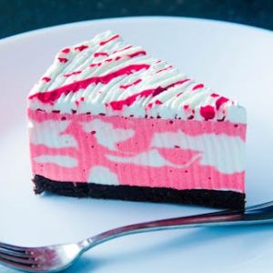 Close-up of a vibrant raspberry cream cake slice with a fork on a plate, perfect for dessert lovers.