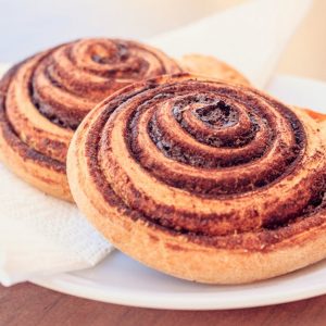 A close-up view of two freshly baked cinnamon rolls served on a white plate.