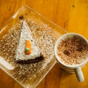 Delicious carrot cake with cappuccino on a rustic wooden table. Perfect for dessert lovers.