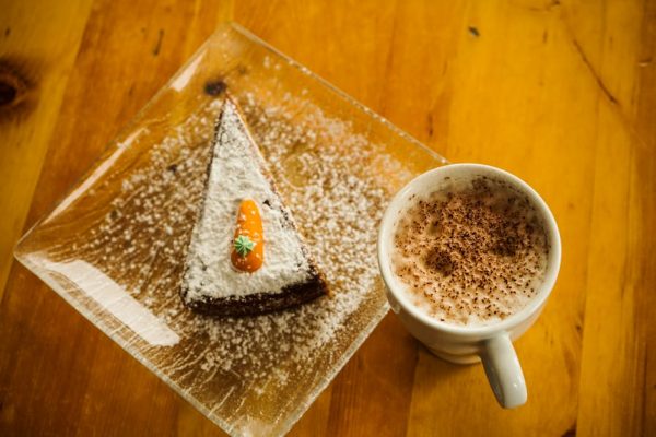 Delicious carrot cake with cappuccino on a rustic wooden table. Perfect for dessert lovers.